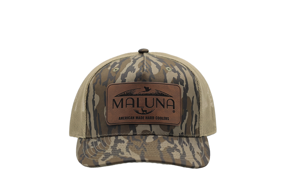 Maluna Camo Snapback Trucker Cap featuring a camo-print front, tan mesh back, and a rectangular leather patch with a logo and text.